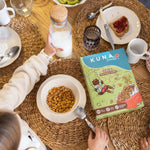 Caja Cereal Manzana Canela Kuna Foods, cereal en caja sin azúcar añadida, con tono verde y mesa de desayuno